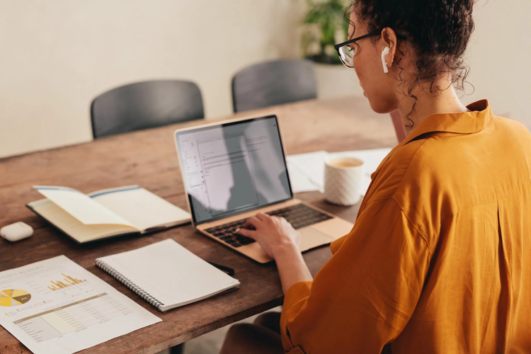 office365-integration Medewerker werkt op laptop met documenten en klantgegevens naast zich